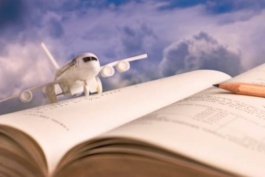 Airplane model on textbook or hardback.  The concept of tourism on holiday or traveling for business.